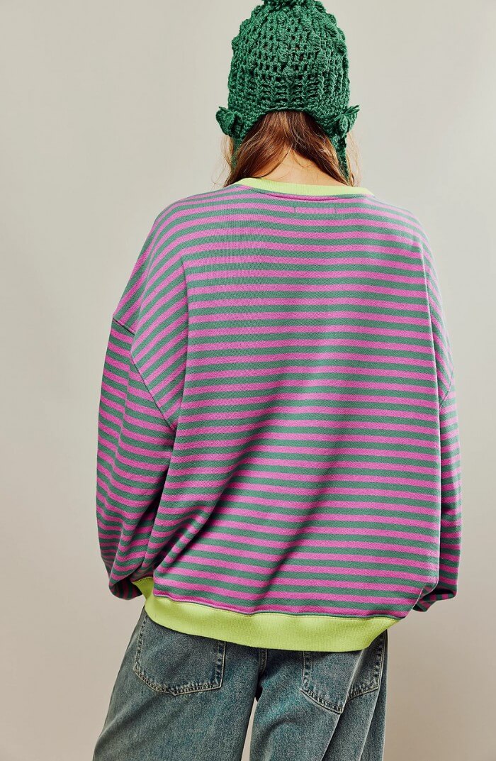 Back view: green and pink striped relaxed pullover with neon yellow hem