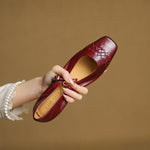 Red Mary Jane ballet flats with square toe and strap buckle, hand holding shoe.