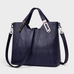 Navy leather handbag with grain texture, top handles, and shoulder strap