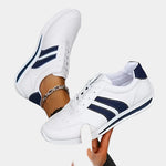 White orthopedic sneakers with navy side stripes, lace-up design and chunky sole