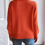 Orange knit sweater back view with ribbed cuffs and rounded hem