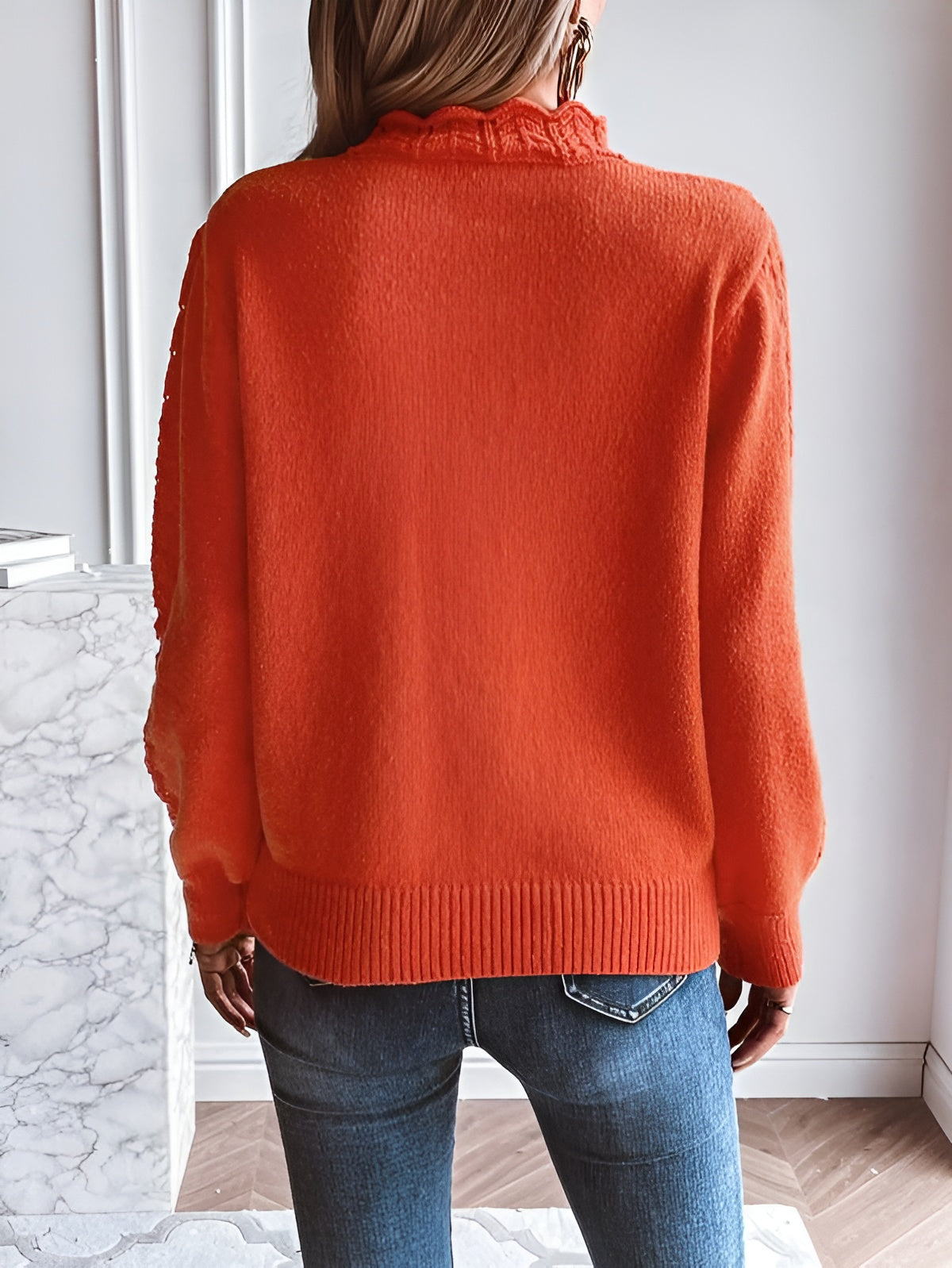 Orange knit sweater back view with ribbed cuffs and rounded hem