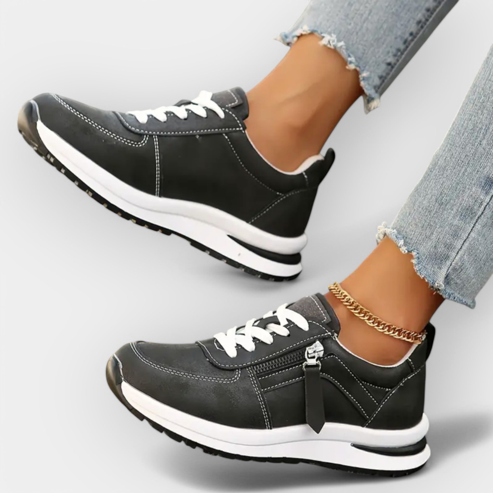 Anatomical black sneakers with white laces, side zipper, and thick white sole.
