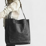 Black leather tote bag with double top handles and front stitched panel.