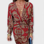 Elegant long-sleeve V-neck dress with red and gold ornate pattern, front knot detail