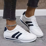 Pair of white lace-up orthopedic sneakers with navy accents and grippy outsole