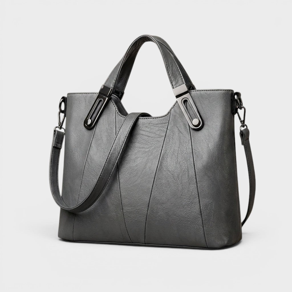 Gray leather handbag with top handles, metal buckles, and adjustable shoulder strap