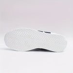 White sneaker outsole with diagonal traction pattern and navy heel detail