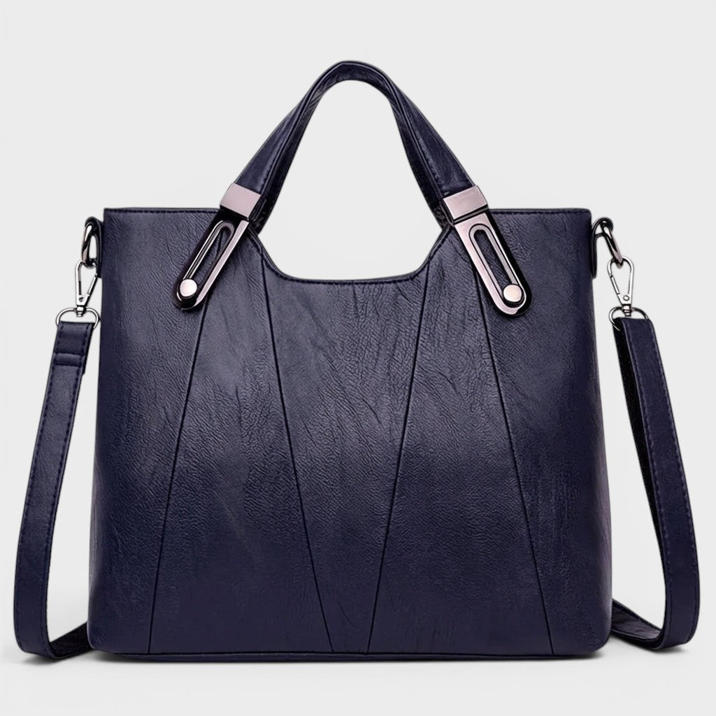 Navy leather handbag with top handles, metal buckles, and crossbody shoulder strap