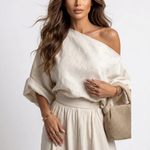 Off-white one-shoulder blouse with loose sleeves and elastic waist, with jogger pants