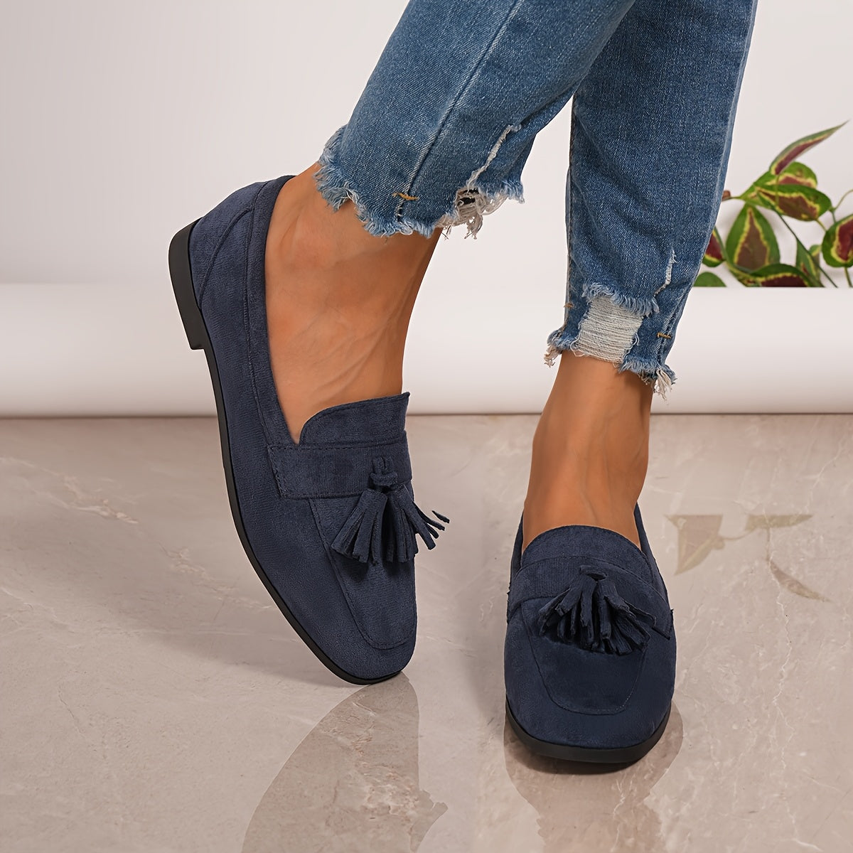 Navy suede tassel loafers on feet, slip-on with low block heel