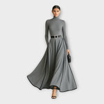 Gray long-sleeve maxi dress with high neck, silver-buckle belt, wide skirt with contrast piping