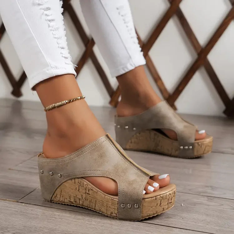 Beige heeled wedge sandal with open toe, studded straps and cork platform