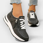 Anatomical black sneakers with white laces, side zipper, and thick white sole.