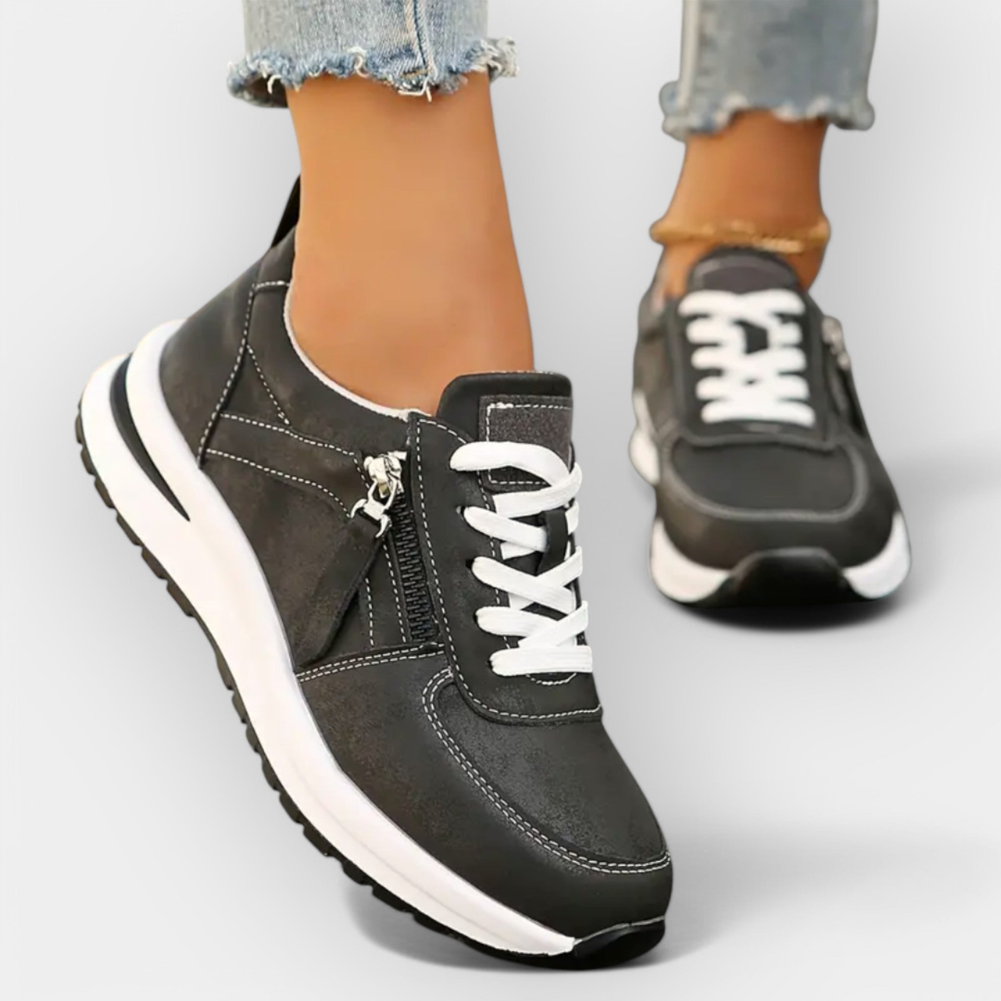 Anatomical black sneakers with white laces, side zipper, and thick white sole.