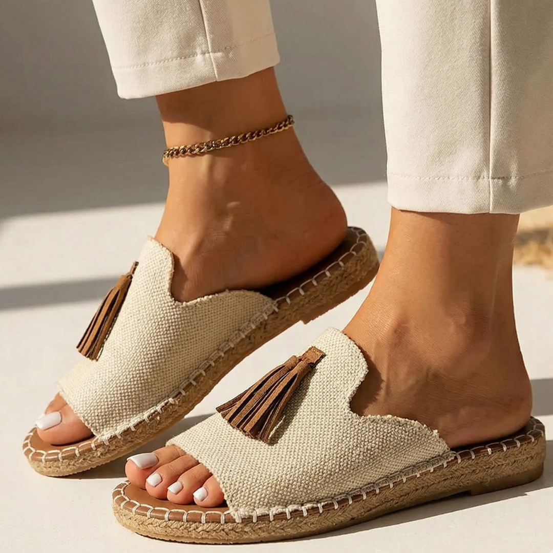 Platform slide sandals with beige woven fabric upper and brown tassels, tan cork sole