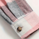 Plaid shirt cuff with brown button and pink, gray, and white check pattern