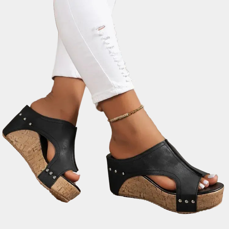 Black heeled wedge sandal with open toe, studded straps and cork sole