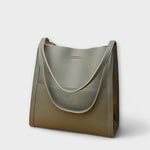 Green natural leather tote bag with curved strap handles and front tab detail
