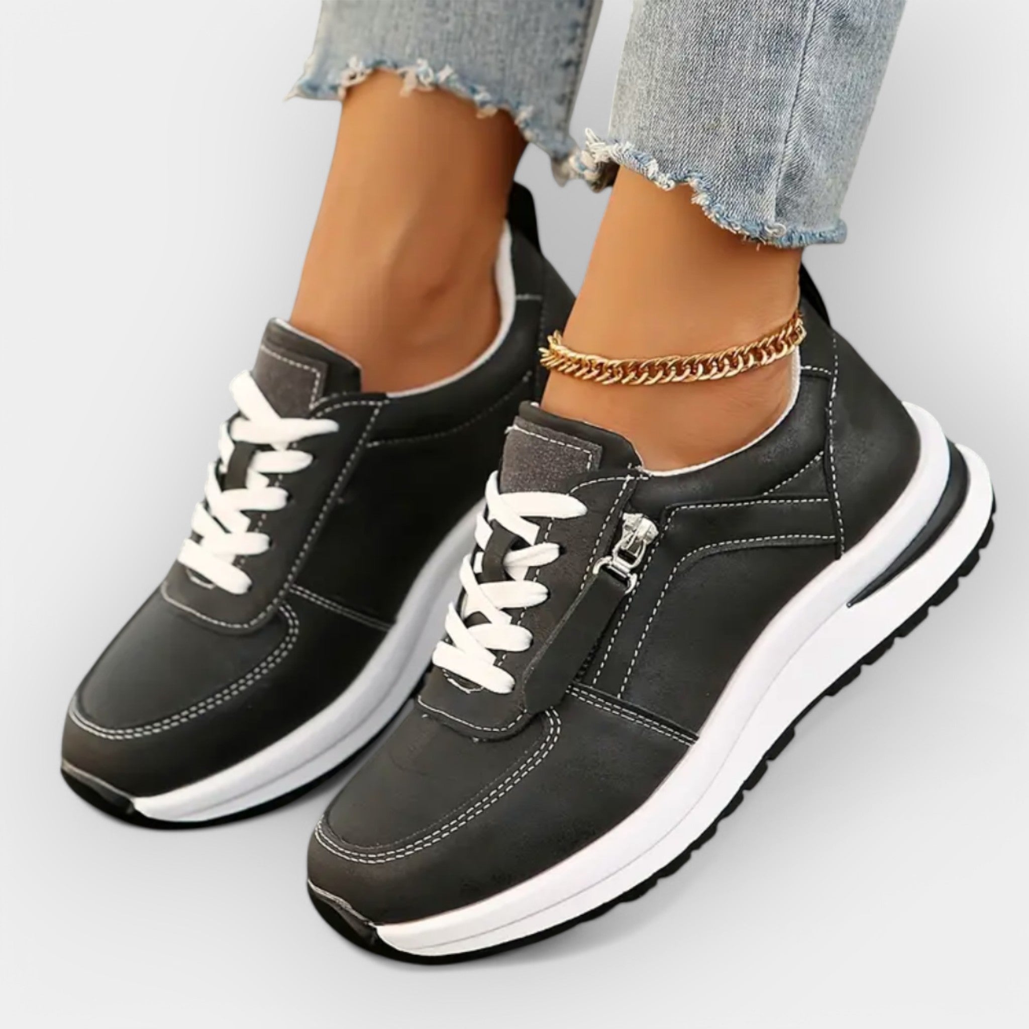 Anatomical black sneakers with white laces, side zipper, and white midsole.