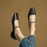 Black Mary Jane flats pair on feet with ankle strap and low block heel.