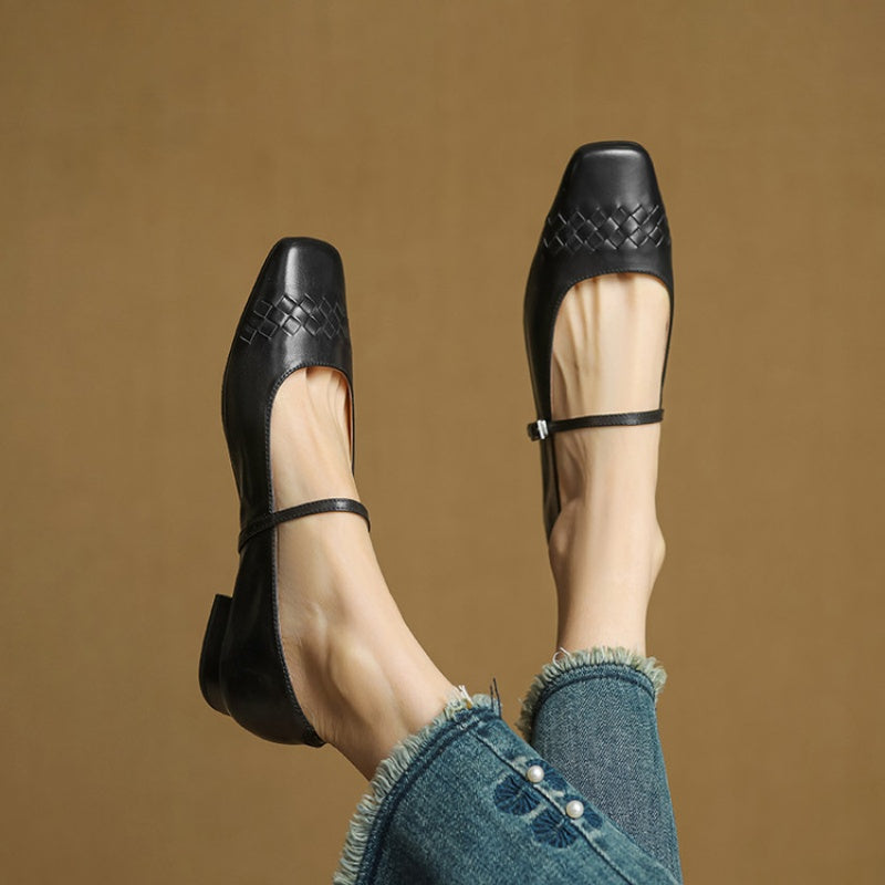 Black Mary Jane flats pair on feet with ankle strap and low block heel.