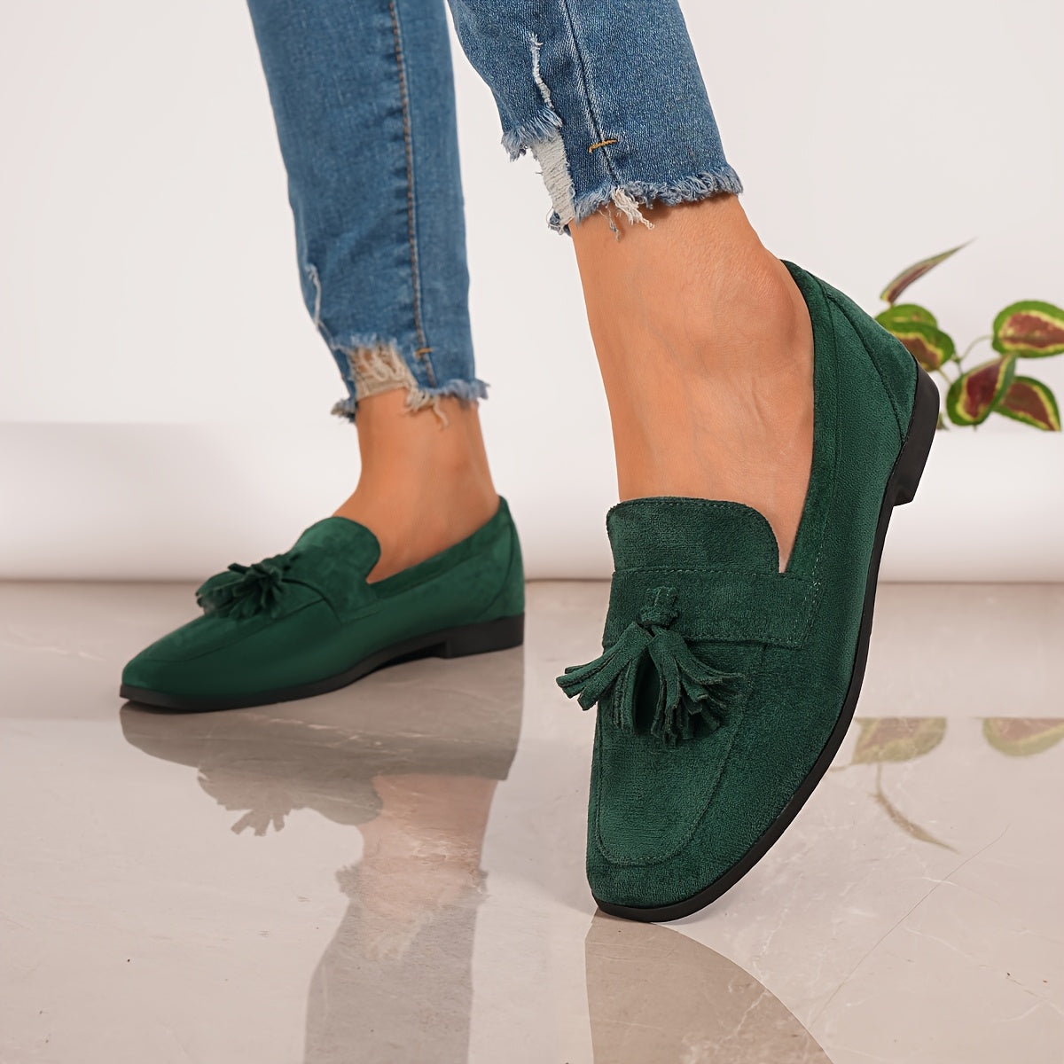 Green suede tassel loafers on feet, slip-on with low block heel