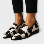 Black-and-white cow-print slip-on loafer with wide vamp strap