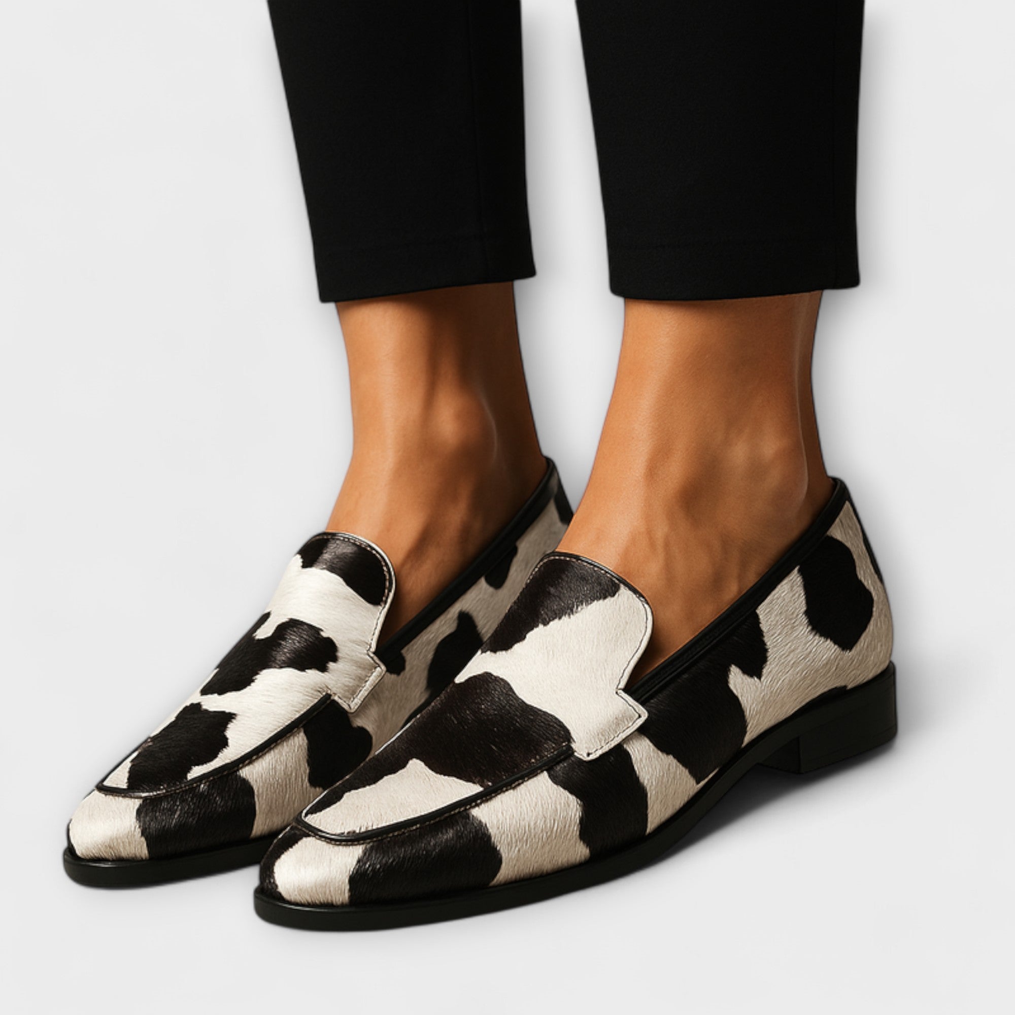 Black-and-white cow-print slip-on loafer with wide vamp strap