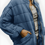 Blue quilted puffer jacket with full-zip front and side pockets, stand collar.