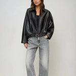 Black zip-front oversized jacket with collar and belted waist, worn with light jeans
