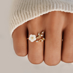 Gold-tone ring with white flower and clear marquise crystals worn on fingertip
