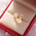 Gold-tone ring with white flower and clear marquise crystals displayed in jewelry box