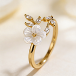 Gold-tone ring with white flower center and clear crystals on vine-like band