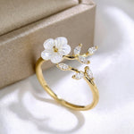 Gold-tone ring with white flower and clear marquise crystals, angled view
