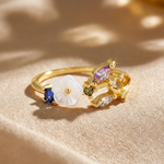 Gold-tone ring with white flower and purple and clear crystals, golden branch
