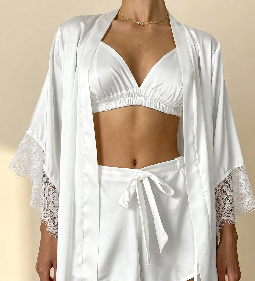 White satin pajama shorts with lace hem and tie waist, worn with matching bra top