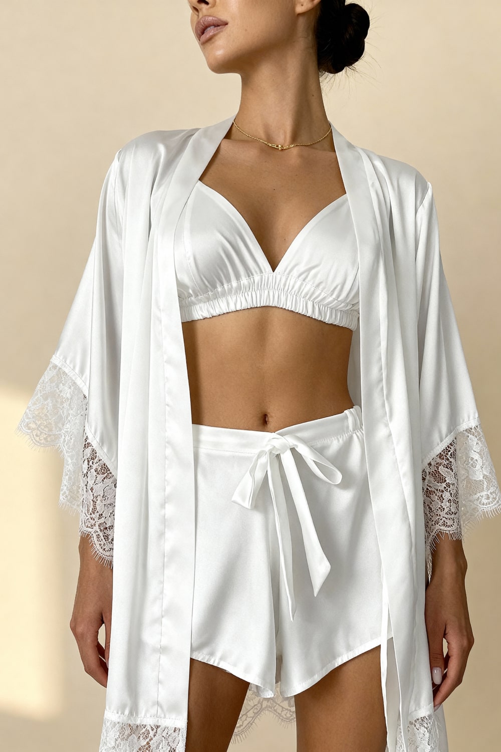White satin pajama shorts with lace hem and tie waist, worn with matching bra top