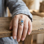 Ocean blue gemstone ring with oval center stone and two small blue accents, on hand