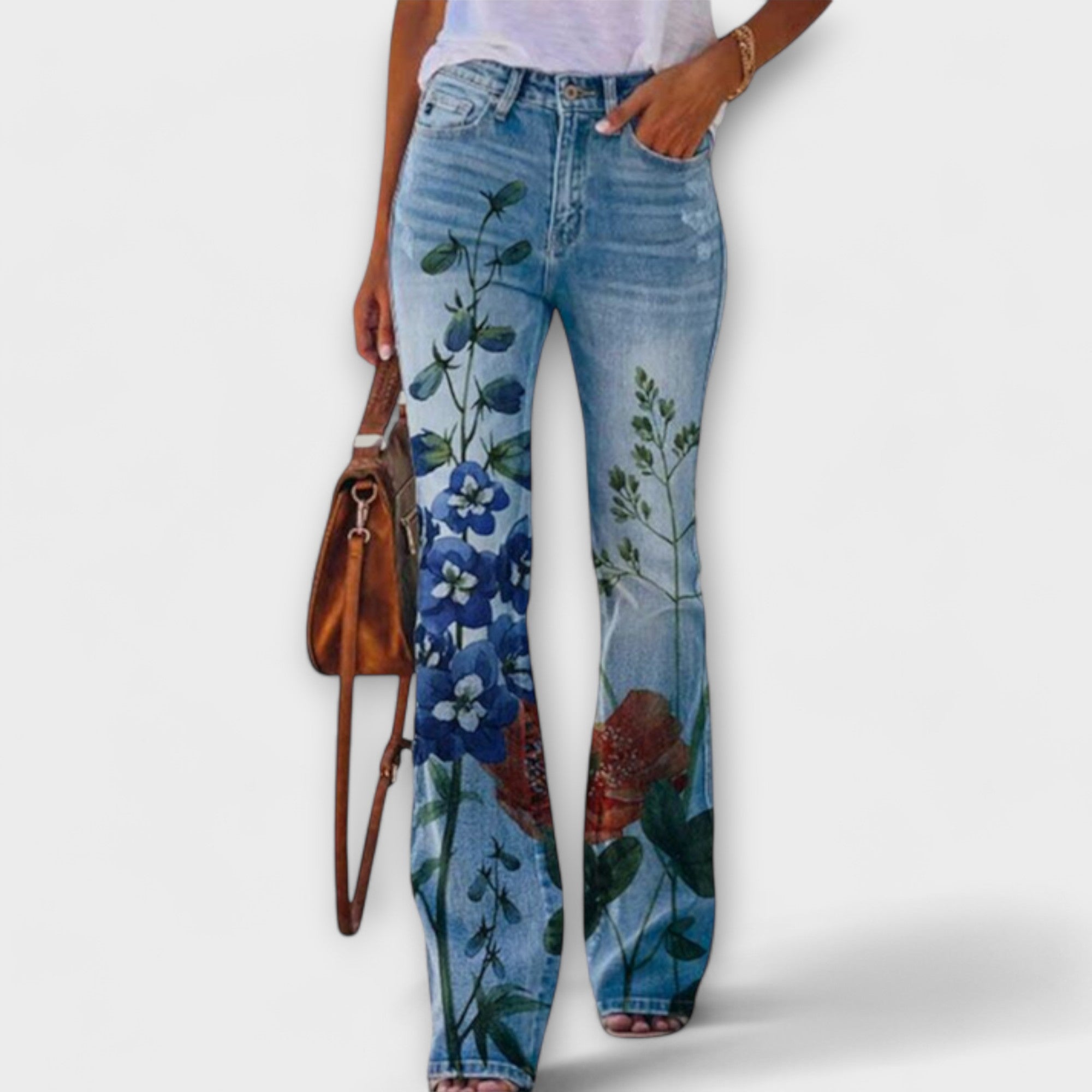 Floral print denim pants with blue wildflower and leafy vine graphics at hem