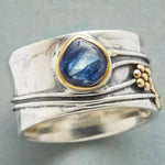Silver-tone ring with oval blue gemstone bezel and gold-tone bead side accents