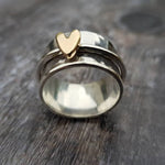 Silver ring with raised gold-tone heart centerpiece on a polished band