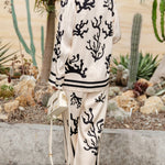 Silk pajama set in cream with black coral print, collared button shirt and wide-leg trousers