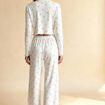 White pajama set from back: long-sleeve crop top and wide capri pants with pink floral print.