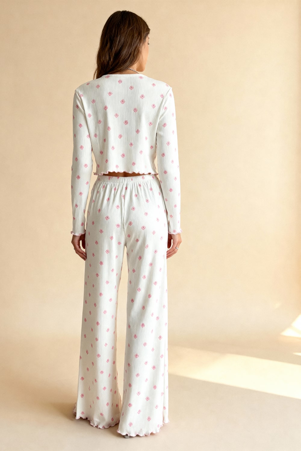 White pajama set from back: long-sleeve crop top and wide capri pants with pink floral print.