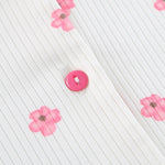 Close-up of white pajama top fabric with pink flower print and pink button placket.
