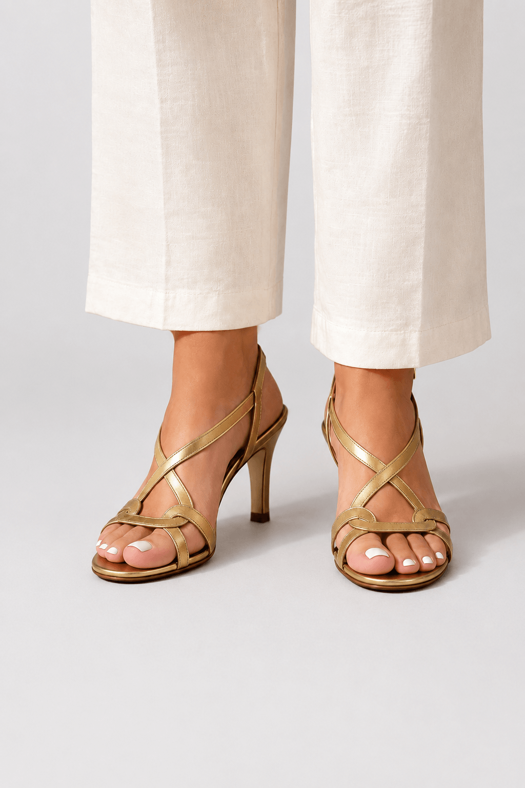 Gold open-toe heeled sandal with slim straps and small charm detail