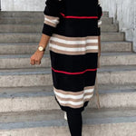 Long black cardigan with beige and white striped bands and thin red stripe.