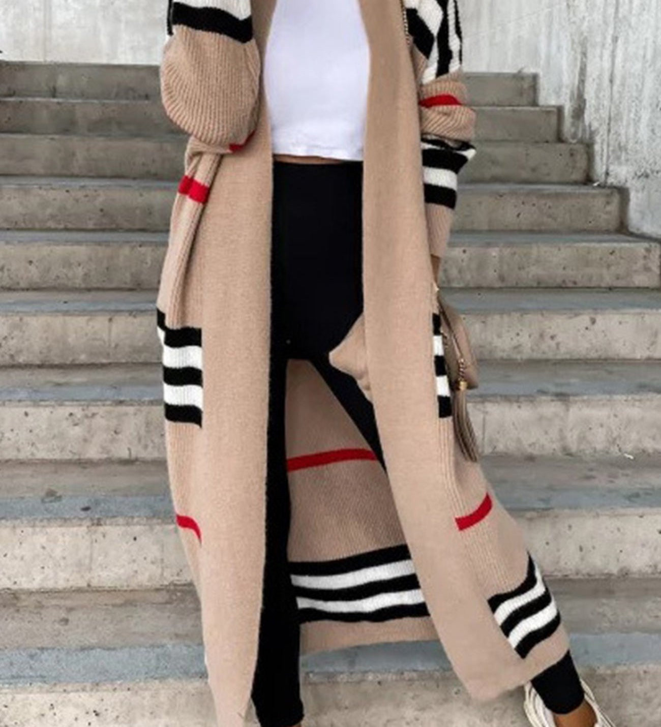 Long beige cardigan with black and white striped sleeves and red accent stripes.