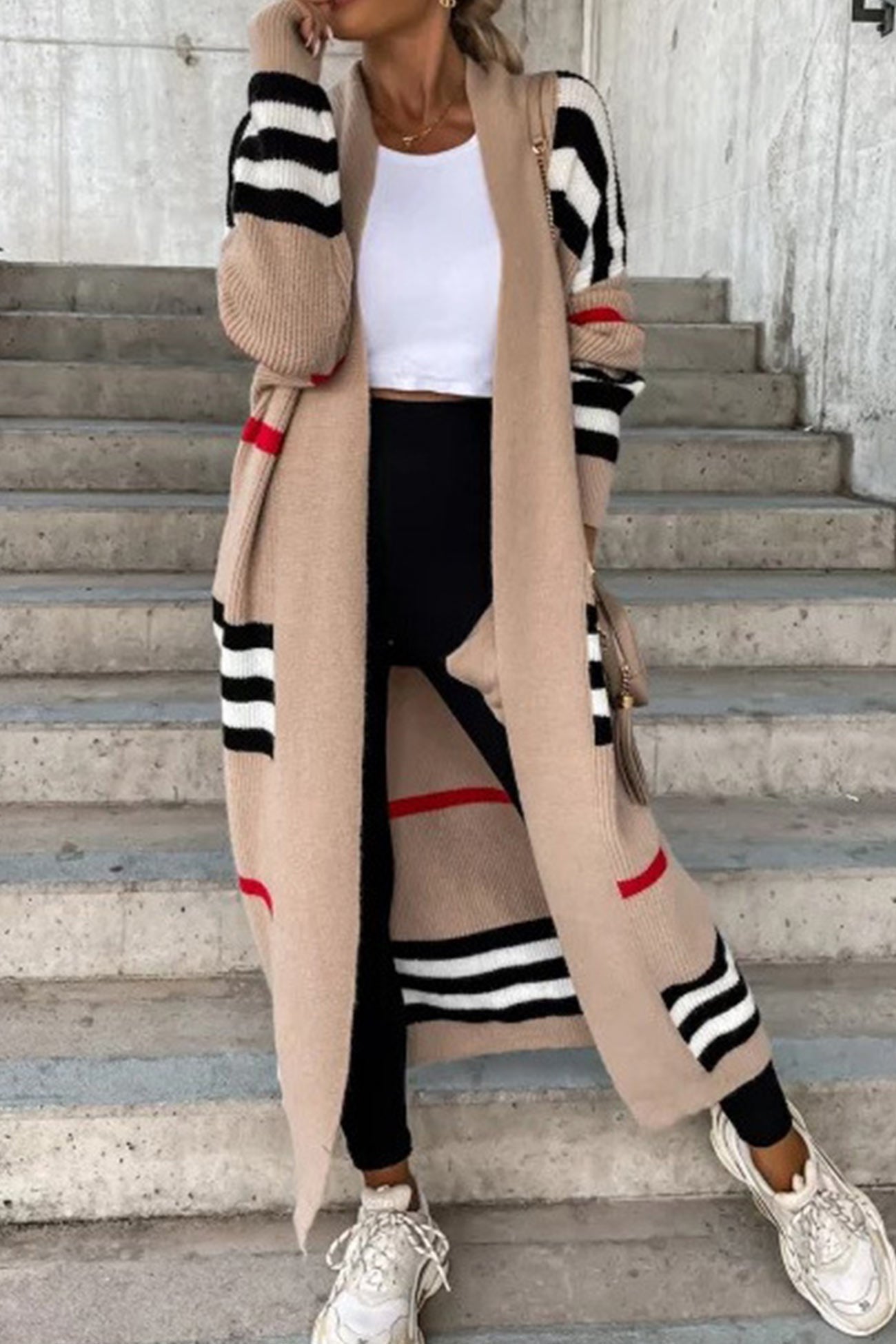Long beige cardigan with black and white striped sleeves and red accent stripes.
